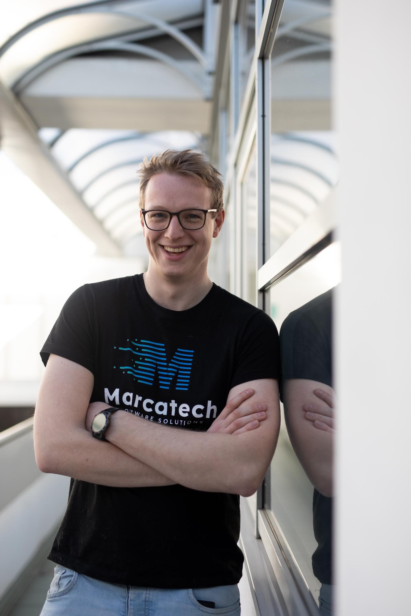 Dominik Markart smiling with arms crossed in a glazed walkway
